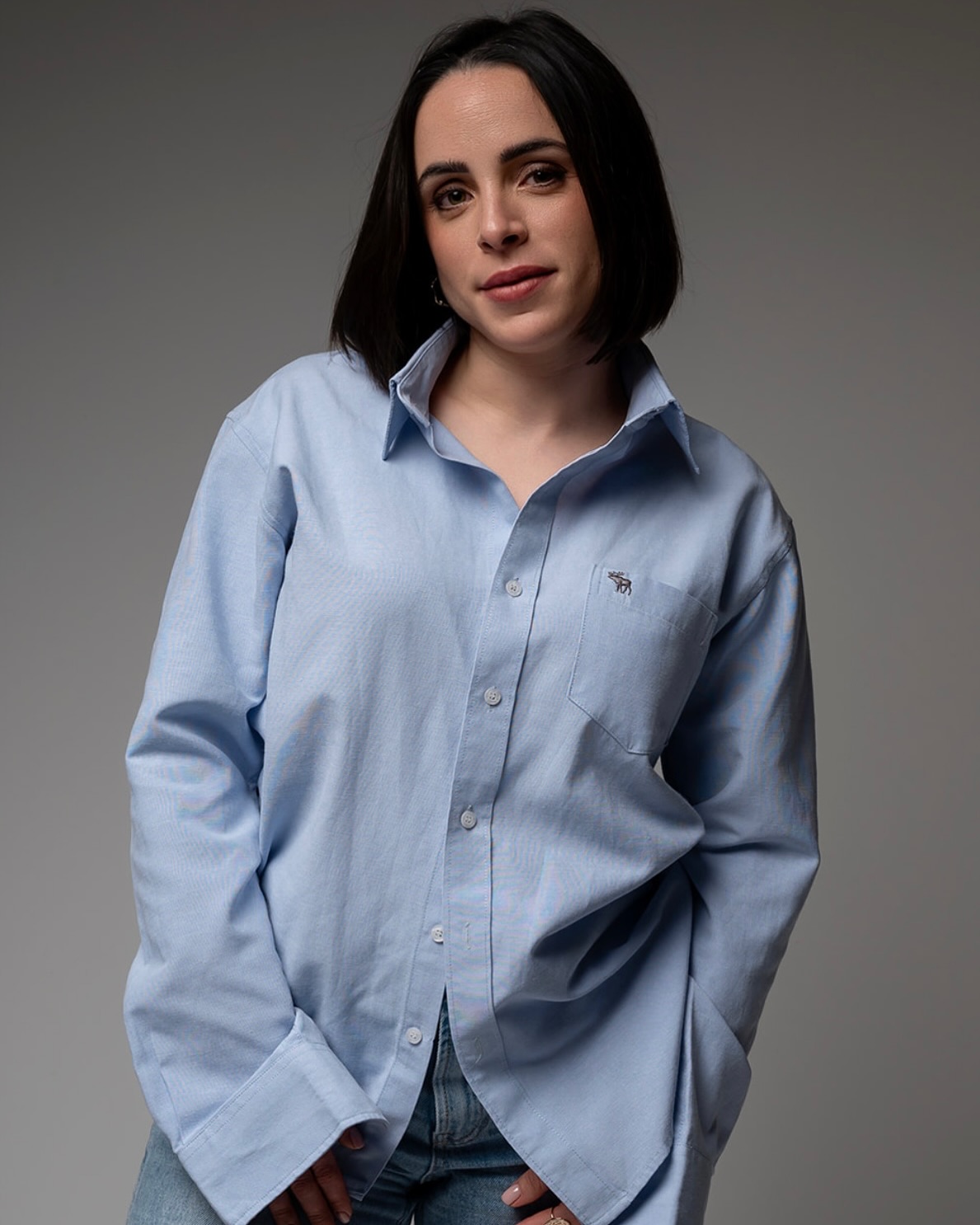 Femme au carré noir en chemise bleu clair, maquillage naturel makeup design à Toulouse, fond gris épuré