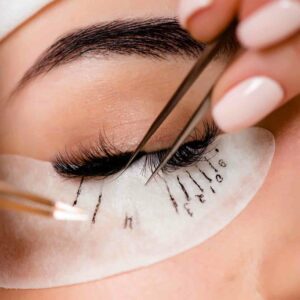 Eyelash extension procedure close up. Beautiful Woman with long lashes in a beauty salon.