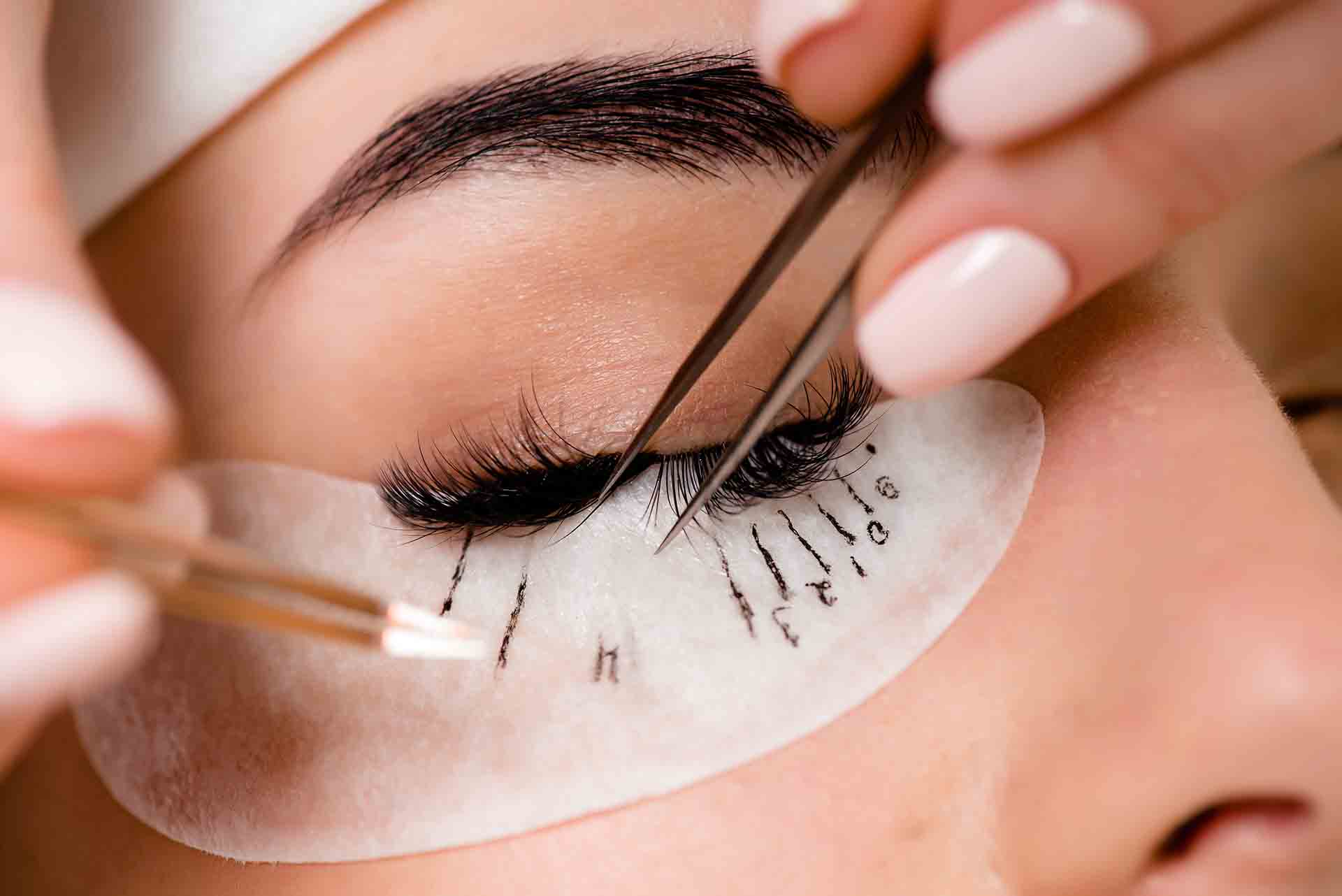Eyelash extension procedure close up. Beautiful Woman with long lashes in a beauty salon.